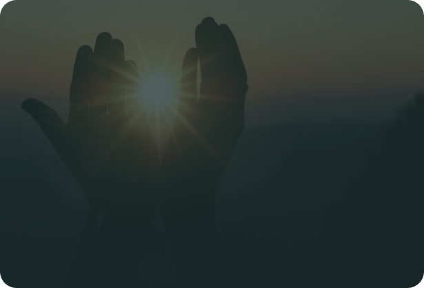 Praying hands silhouetted against a warm light