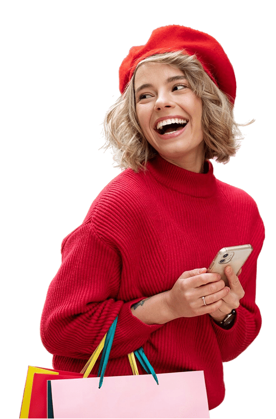 Smiling woman in a red sweater holding a smartphone and shopping bags