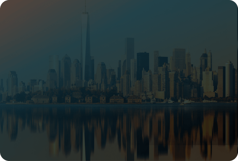Night-time city skyline reflected in water, lit by warm sunset light